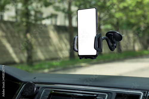Car holder with modern mobile phone on windshield of automobile. Mockup for design photo
