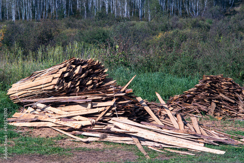 Lumber stockpiled in the open air on the green grass. photo