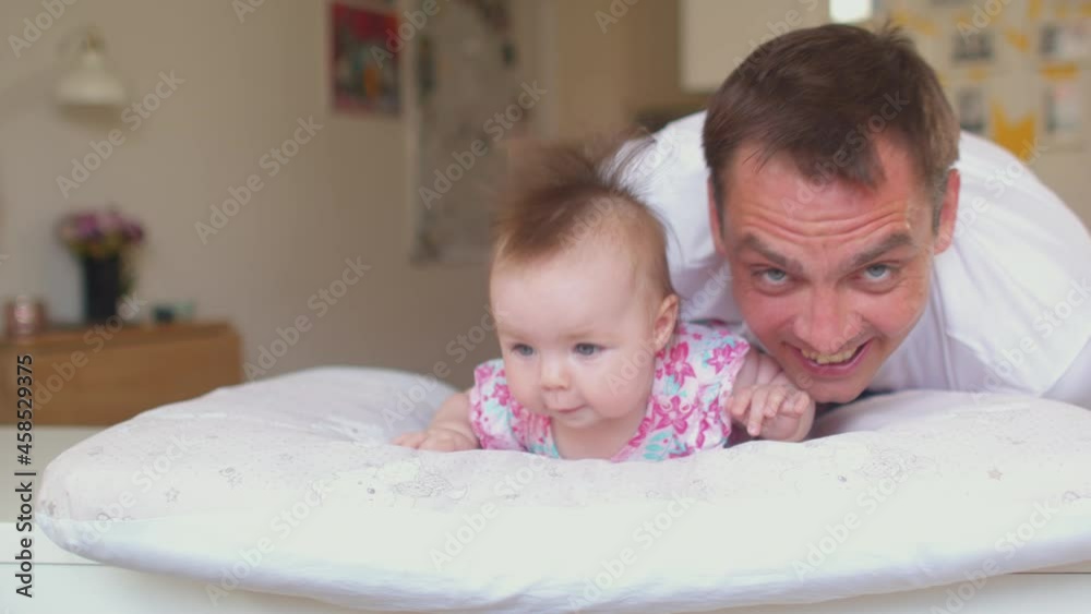 The baby lies on her stomach while supervised. Happy loving family