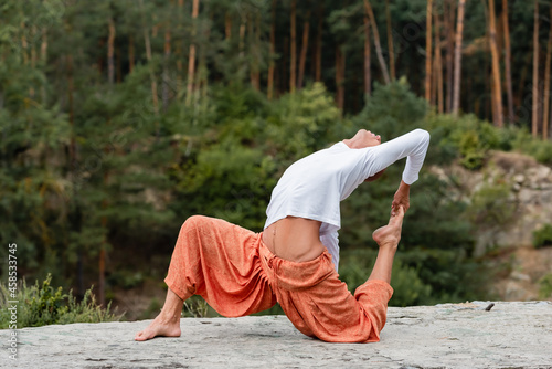 Foto barefoot buddhist practicing crocked monkey pose in forest