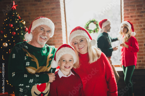 Photo portrait of grandparents celebrating winter holidays together with grandson wearing red headwear