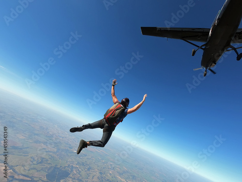 Skydiver jumps from a black plane on a hot day with clear skies.