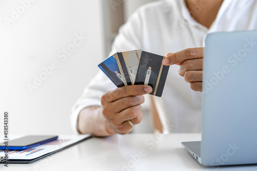 Business man choosing the right credit card for online spending, Online payment, man hands holding a credit card and using smartphone and choose some product what for online shopping.