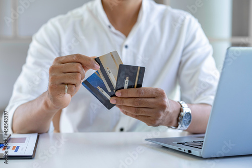 Business man choosing the right credit card for online spending  Online payment  man hands holding a credit card and using smartphone and choose some product what for online shopping.