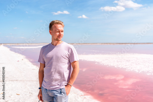 A young man walks on a salty pink lake with a blue sky. A peaceful landscape and relaxation
