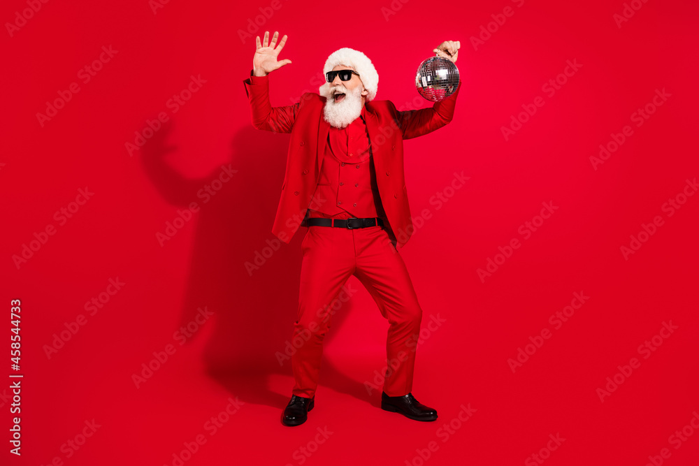 Photo of funky positive santa claus dance hold glitter ball wear sunglass x-mas hat suit on red color background Photo of funky positive santa claus dance hold glitter ball wear sunglass x-mas hat suit on red color background