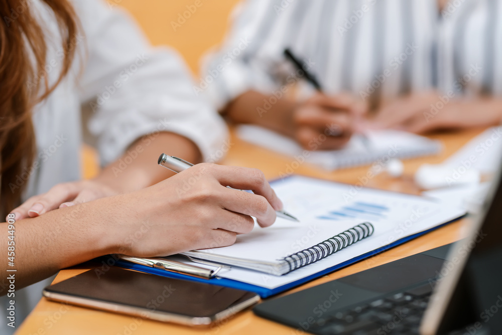 Close-up of a businesswoman hand holding a pen and taking notes report of work at the meeting room. Close-up of a businesswoman hand holding a pen and taking notes report of work at the meeting room.
