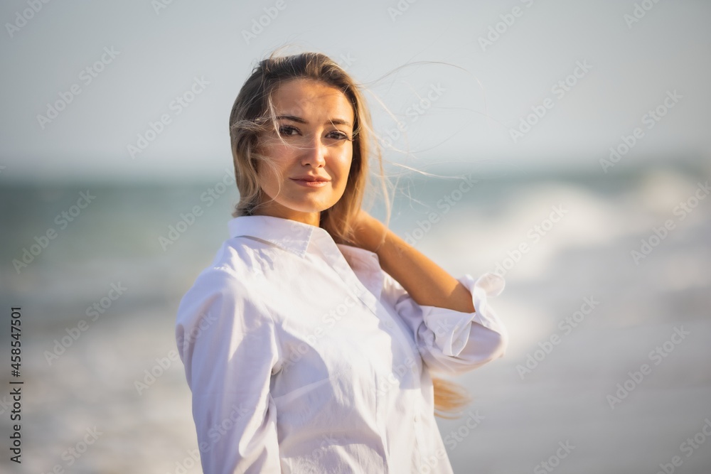 Portrait of a girl in a blue swimsuit and white shirt against the background of the blue sea and clear sky Portrait of a girl in a blue swimsuit and white shirt against the background of the blue sea and clear sky
