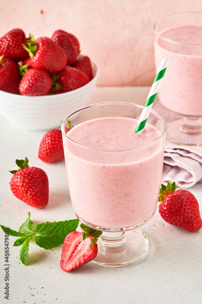 Two strawberry smoothie or milkshake with berries and mint in glass on light pink background. Summer drink shake, milkshake and refreshment organic concept. Healthy dieting, vegetarian food concept. Two strawberry smoothie or milkshake with berries and mint in glass on light pink background. Summer drink shake, milkshake and refreshment organic concept. Healthy dieting, vegetarian food concept.