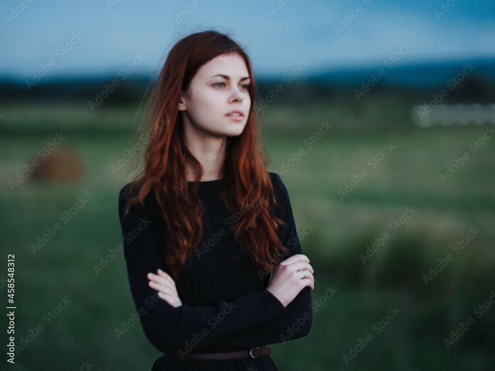 pretty red-haired woman in black dress in the field pretty red-haired woman in black dress in the field