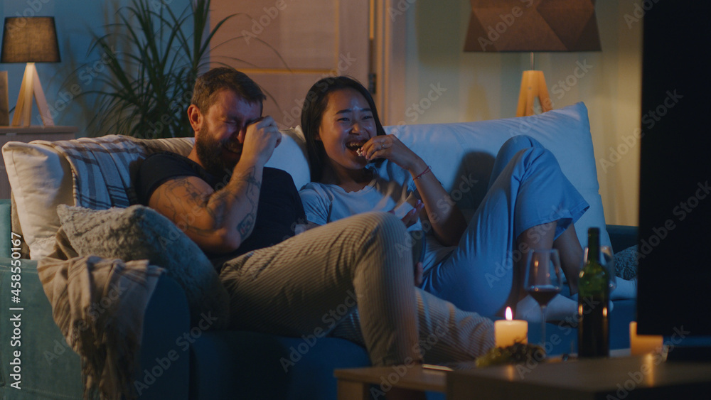 Obraz premium Diverse couple watching comedy film in evening