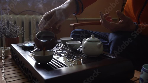 man pouring puer tea in teapot at traditional chinese tea ceremony set of equipment photo