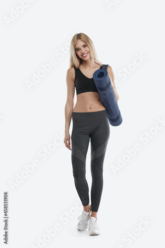 Smiling european sports woman holding fitness mat