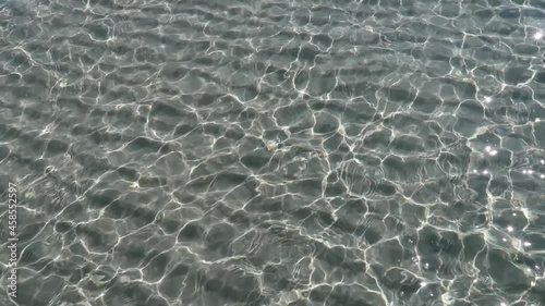 clear azure summer sea water transparent surface clear sea sand beach.  transparent water in motion with glare and sunbeams