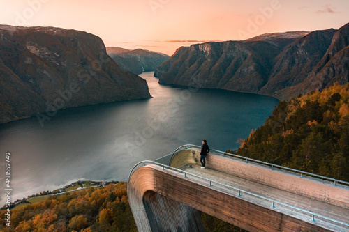 A Tourist Views Aurlandsfjord From the Stegastein Lookout in Norway at Sunset photo