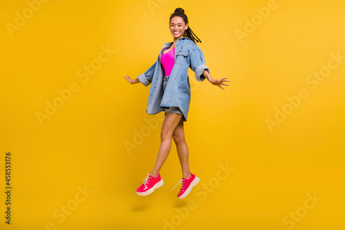 Full size profile side photo of young black girl happy positive smile jump up walk travel isolated over yellow color background