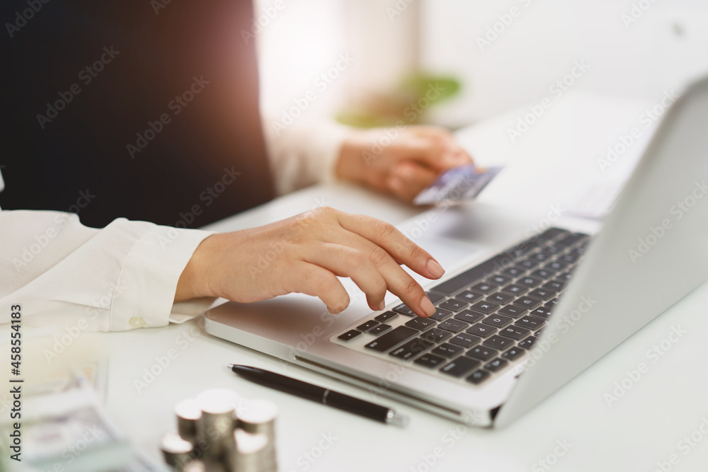 Woman spending money on Online shopping. Hands holding credit card and using laptop working at home e-commerce and internet banking concept Woman spending money on Online shopping. Hands holding credit card and using laptop working at home e-commerce and internet banking concept