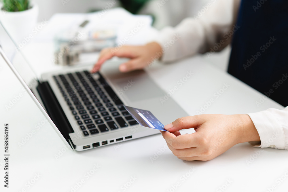 Fototapeta premium Woman spending money on Online shopping. Hands holding credit card and using laptop working at home e-commerce and internet banking concept