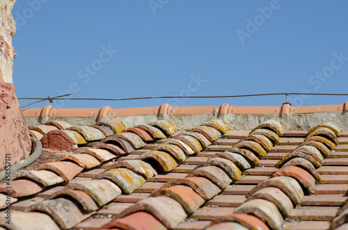 House, gabled roofs with tiles, upper ridge and exposed ridge tiles. The tiles are made of earthenware or terracotta, an ancient design of curved and flat tiles that form rainwater drains on a roof. photo