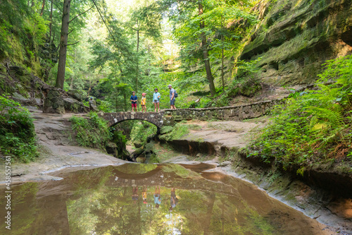 Family hiking outdoors across a bridge in the forest near Hocking Hills State Park in Ohio
 photo