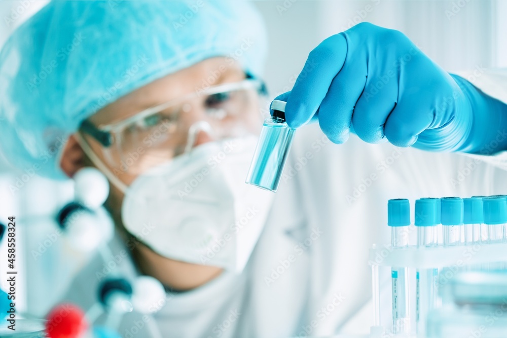 A scientist in the COVID-19 medical vaccine research and development laboratory holds a syringe with a liquid vaccine to study and analyze antibody A scientist in the COVID-19 medical vaccine research and development laboratory holds a syringe with a liquid vaccine to study and analyze antibody