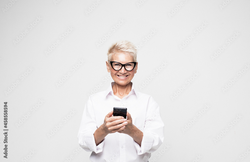 Pretty senior female in casual outfit using modern smartphone