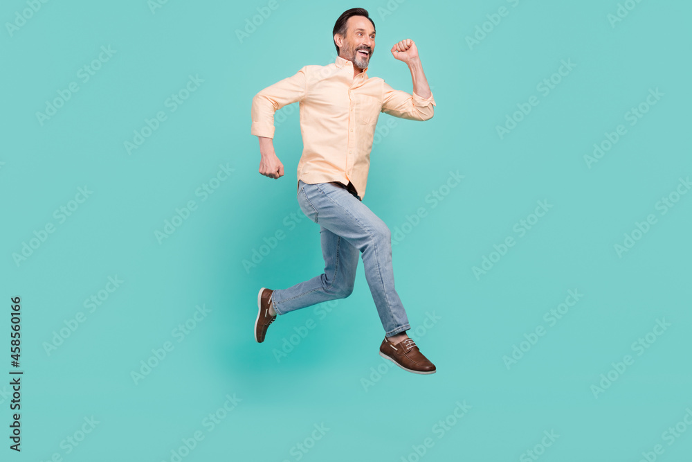 Full length photo of funky mature man run wear shirt jeans sneakers isolated on teal color background Full length photo of funky mature man run wear shirt jeans sneakers isolated on teal color background