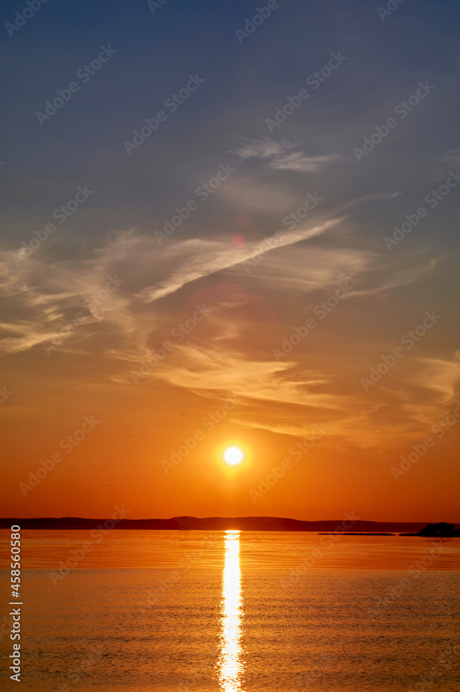 Evening sunset over the lake in orange tones. Evening sunset over the water. Sunset scene.
