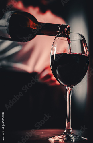 waiter pouring red wine into a glass in cafe or bar
