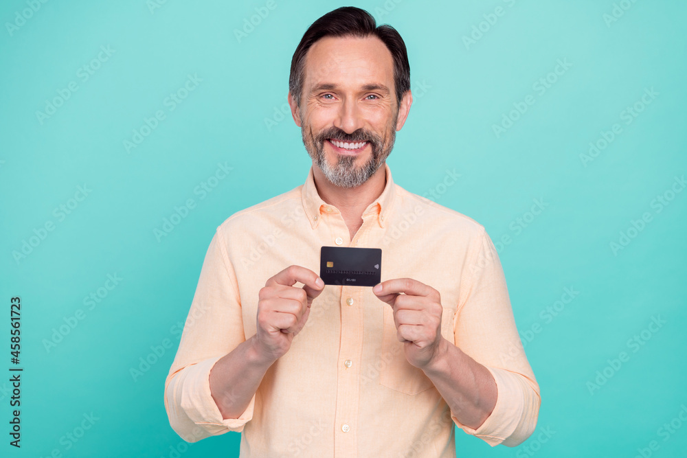 Photo of smiling cheerful handsome male hold demonstrate credit debit card isolated on bright turquoise color background Photo of smiling cheerful handsome male hold demonstrate credit debit card isolated on bright turquoise color background