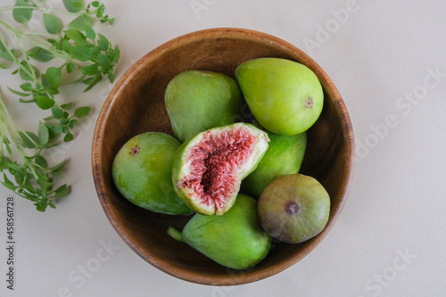 Juicy and ripe pear-shaped figs lie on a plate and cut against a light background.

