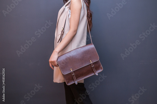 Woman carries brown leather messenger bag in the hand photo