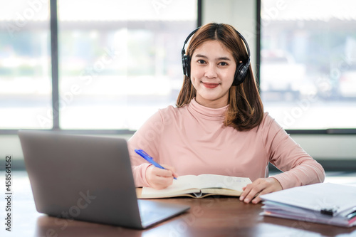 Young Woman College Student Wears Headphone Look at Laptop Study Online at Home