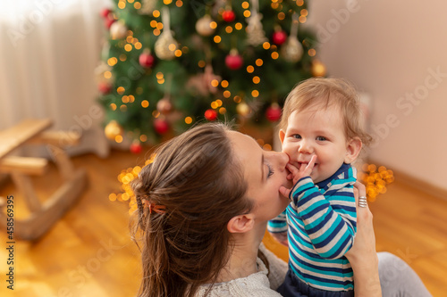 Mother kissing her son while playing at home on Christmas day