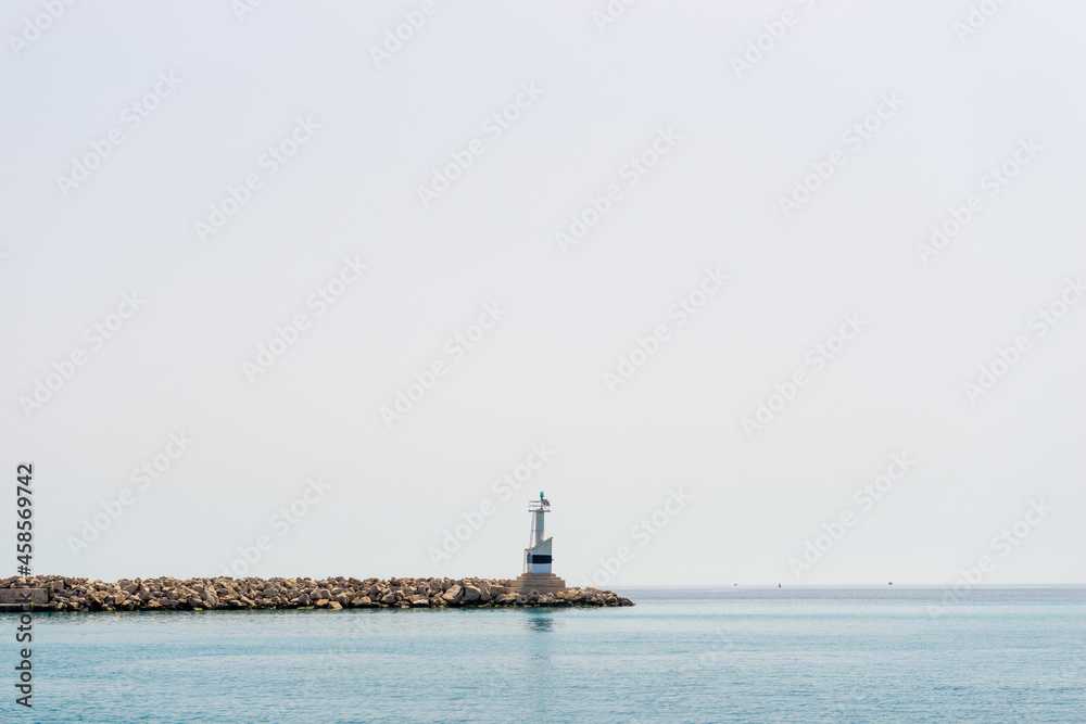 Lighthouse on ocean coastline over sky