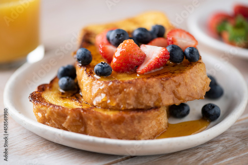French toast with berries and honey on plate, closeup view, selective focus