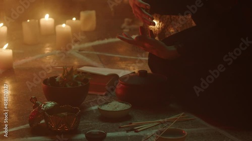 Witch woman sitting in pentagram circle and cooking potion. Evil sorceress making rite and sacrifices at night, using black witchcraft, candles on floor. Halloween tradition, usa holiday. 