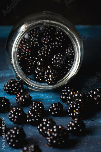 moras en un frasco de cristal sobre fondo azul texturizado photo