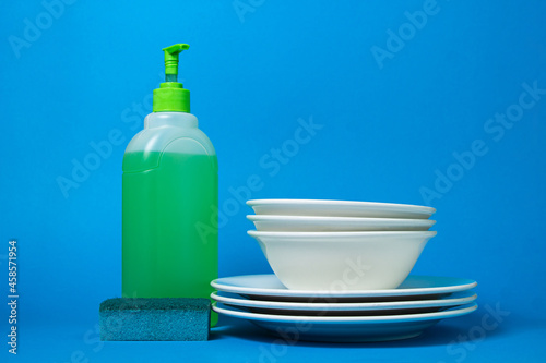 Detergent next to clean plates on a blue background. Ecological household chemicals © Ruzanna