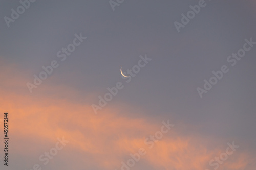 Φωτογραφία Small new moon in a blue and orange sky