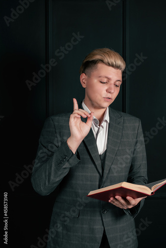 Businessman reads a book on the background of a black wall.