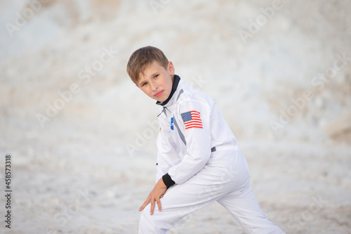 Young boy dressed as an American astronaut posing against the backdrop of the white mountains.