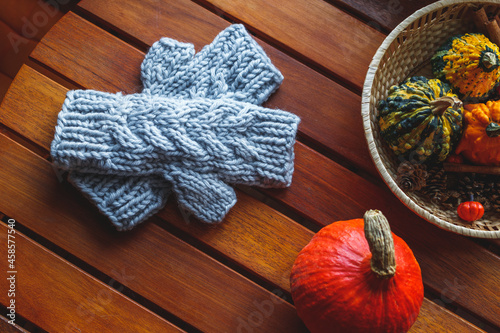 Knitted fingerless glove on wooden table. Autumn decoration with pumpkins