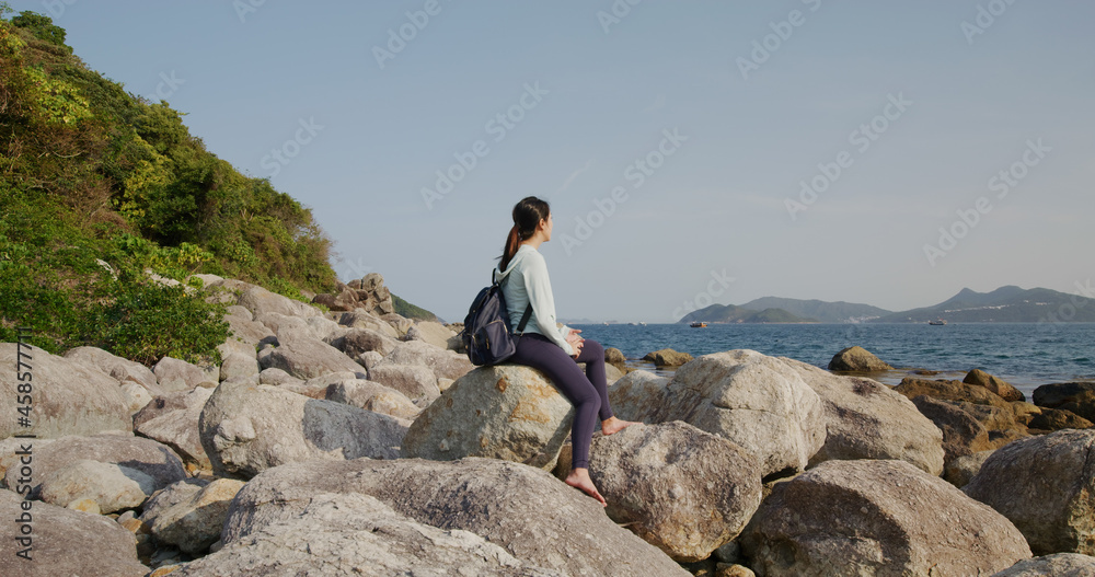 Obraz premium Woman sit on the rock and enjoy the sea view at beach