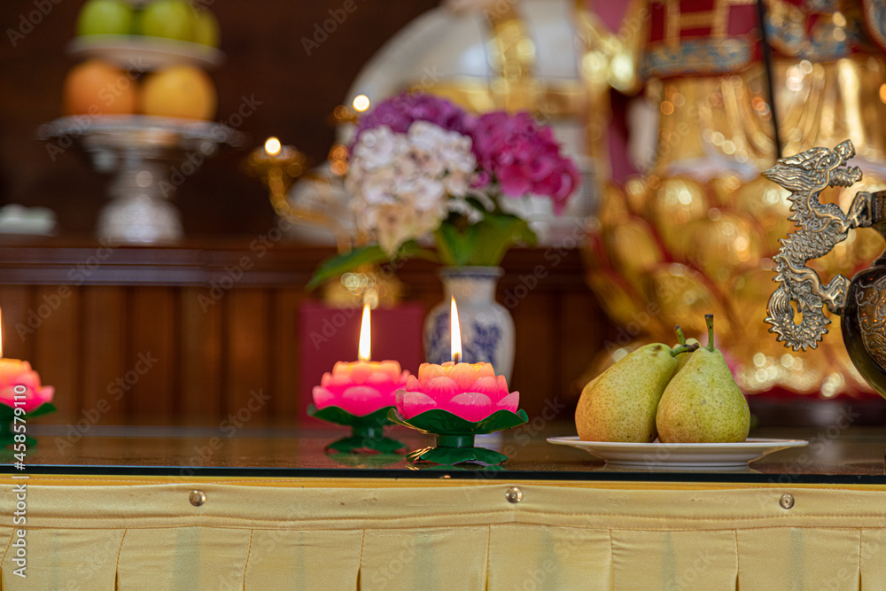 Closeup shot of a flower-shaped melted candle near the plates with fruits.