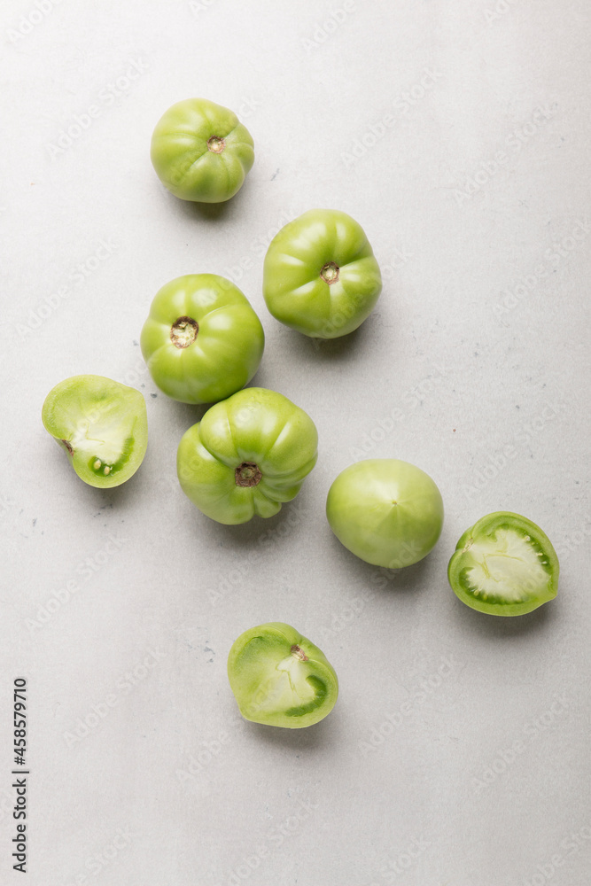 Green tomatoes for conservation on a gray background. Unripe tomatoes for harvesting. Cutaway tomato. Green tomatoes for conservation on a gray background. Unripe tomatoes for harvesting. Cutaway tomato.