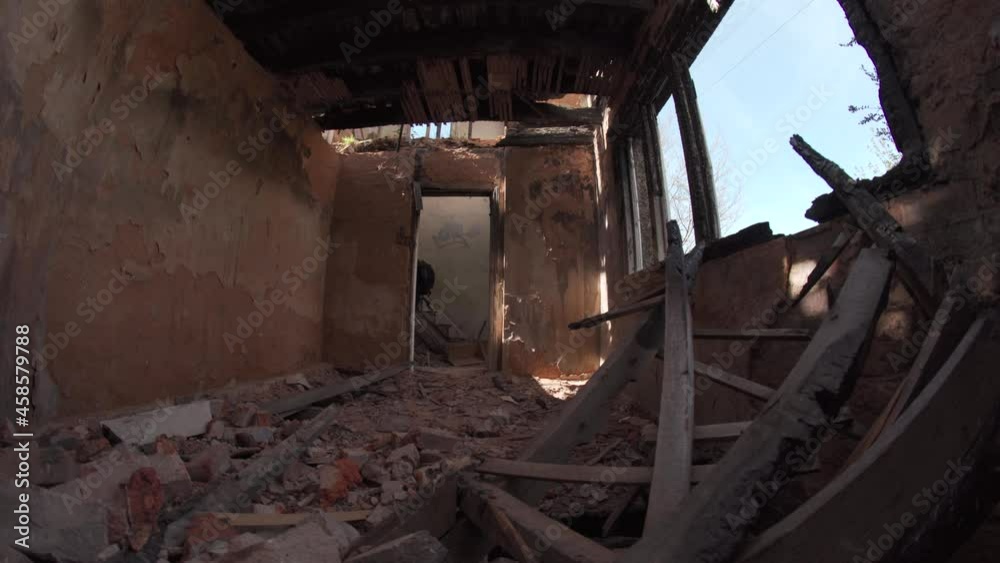 A man walking inside an old abandoned derelict house full of rubble A man walking inside an old abandoned derelict house full of rubble