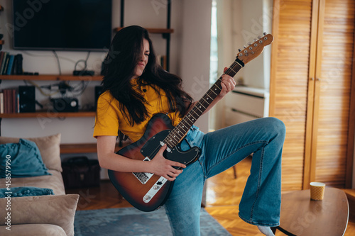 Woman dancing and playing guitar in the living room at home