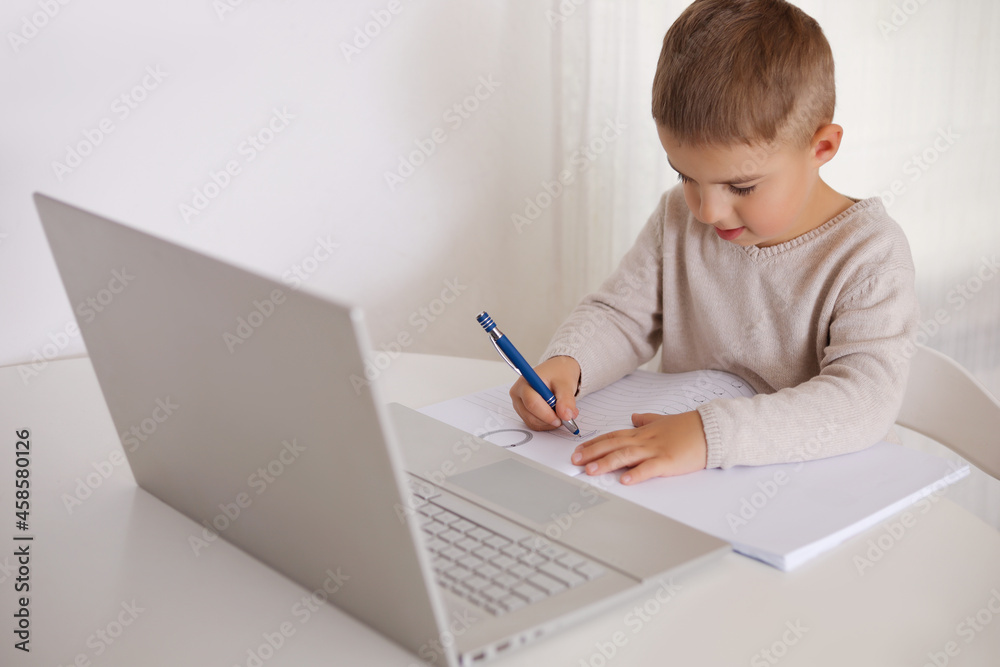 Little boy learning with a laptop at home. Online education and e-learning concept. Home quarantine distance learning. Modern kid and education technology. Little boy learning with a laptop at home. Online education and e-learning concept. Home quarantine distance learning. Modern kid and education technology.