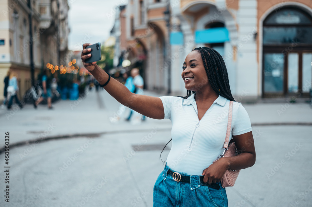 African american woman taking selfie with her smartphone while out in the city